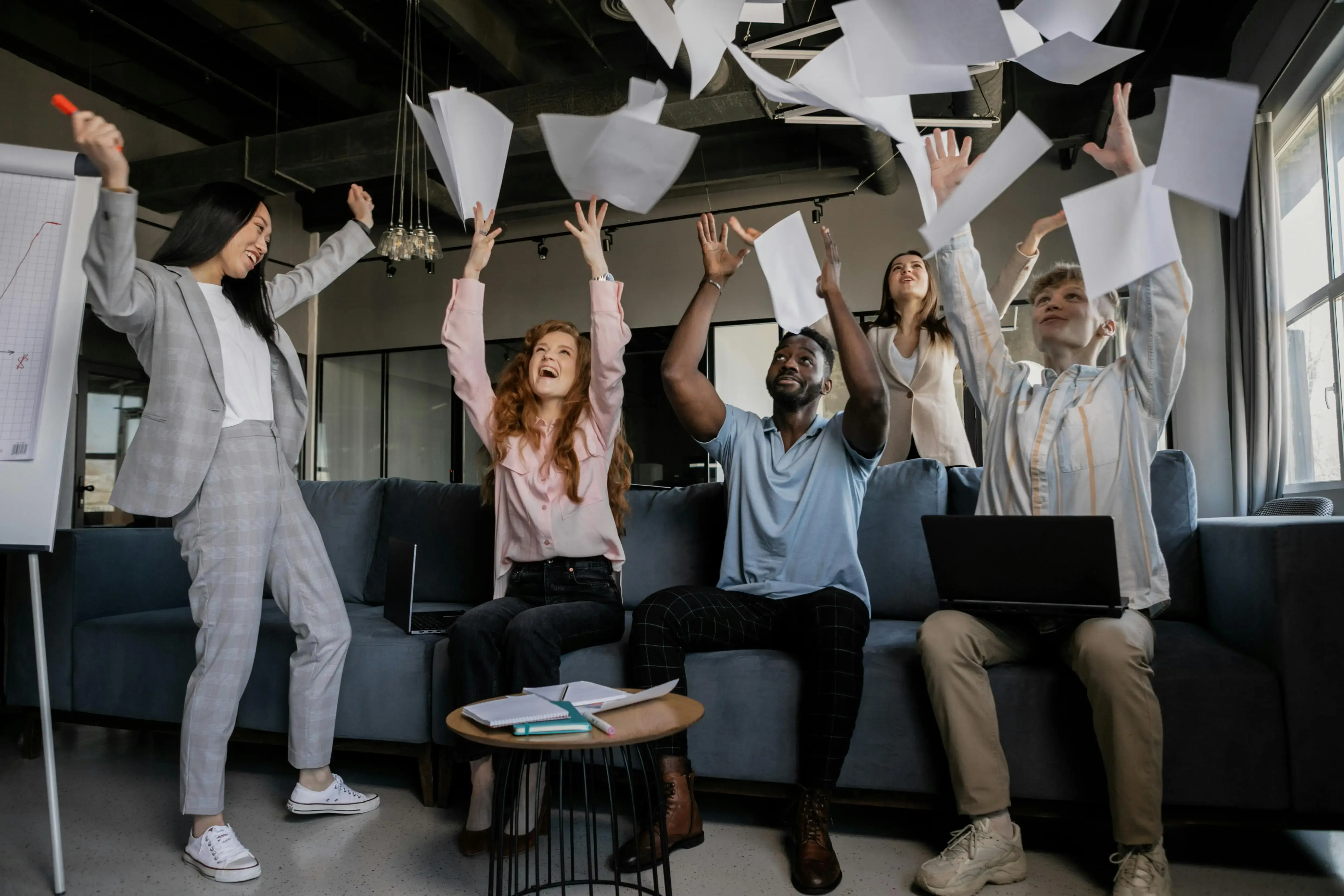 Équipe qui célèbre en lançant des feuilles de papier en l'air au bureau